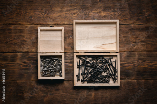 Screws and nails work tools in the boxes on the brown flat lay workbench background.