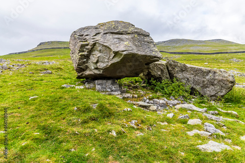A view of a masive glacial erratic boulder resting on limestone pavement on the southern slopes of Ingleborough, Yorkshire, UK in summertime photo