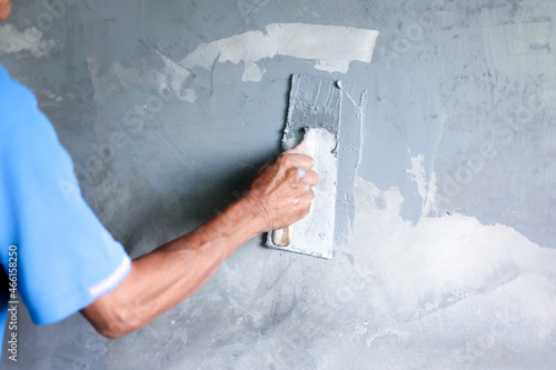 Painter painting wall with rectangular trowel.