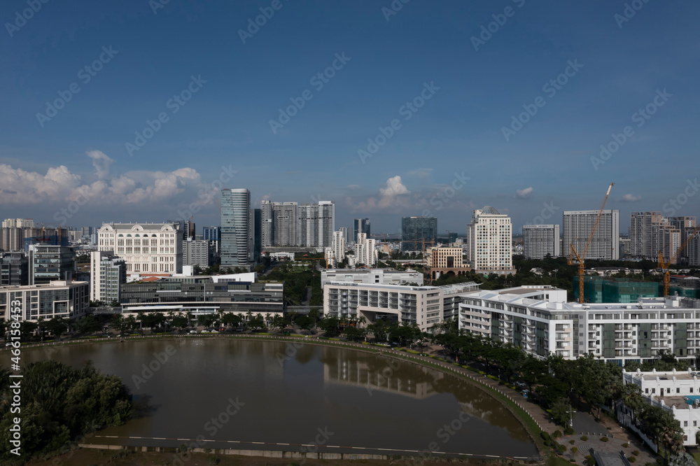 Ultra modern city and lake reflection on sunny, clear day featuring a mixture of architectural styles. Phu My Hung, District 7, Ho Chi Minh City, Vietnam