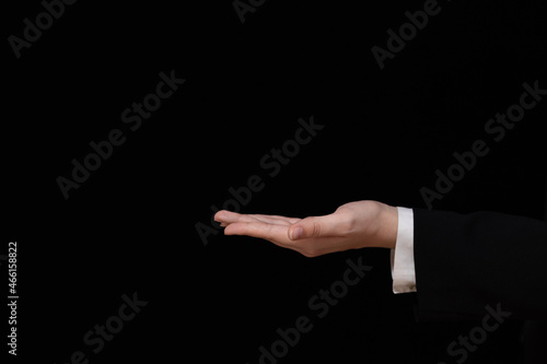 hand of businesswoman with palm up on black background, offer, show gesture, business background mockup, hold something on an open hand