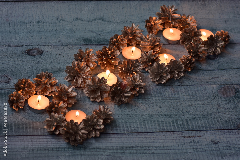 Christmas background of festive silver pine cones in fire burning candles