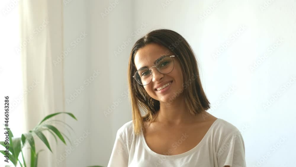 Happy young woman in eyeglasses looking at camera from domestic room of her house. Beautiful satisfied lady with short hair smiling while facing camera at modern apartment. Female youth smiling at hom