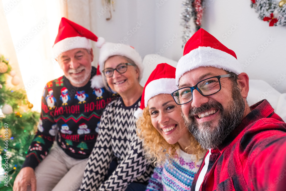 Four young and old people having fun and showing at the camera their gift or present at the camera - celebrating Christmas together. Four young and old people having fun and showing at the camera their gift or present at the camera - celebrating Christmas together.