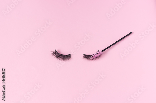 Artificial eyelashes on a pink background and an eyelash brush. The concept of eyelash extensions, makeup.
