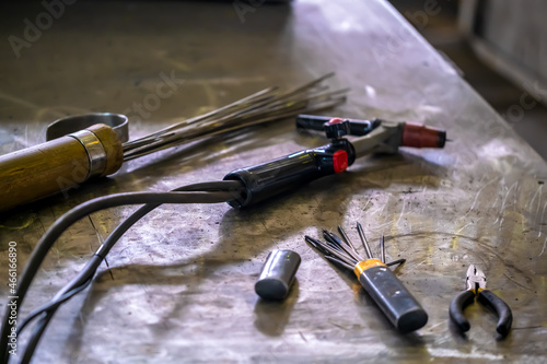 TIG welding. The workplace of the welder, welding equipment on a metal table. Welding torch, stainless filler wire, tungsten non-melting electrodes, pliers. photo
