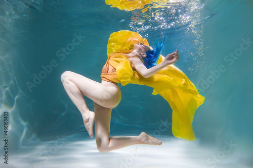 Girl dancing underwater in a yellow dress