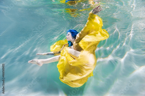 Girl in a yellow dress underwater with water highlights