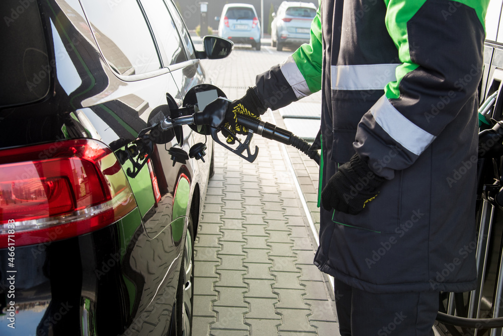 A gas station employee fills a car at a gas station