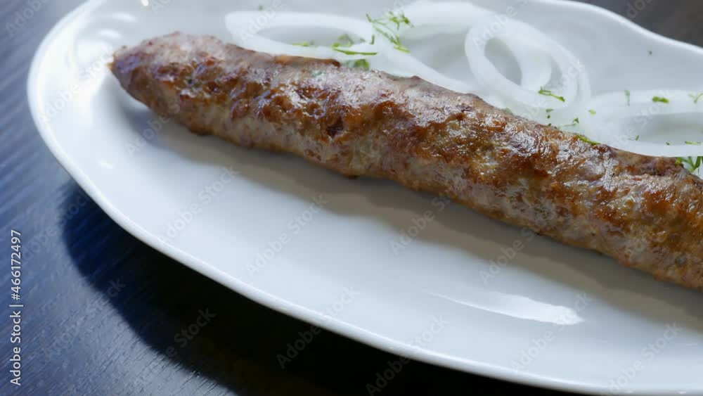 Beef kebab with onion rings on a white plate Beef kebab with onion rings on a white plate