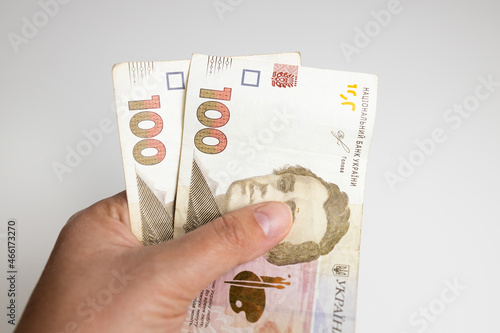 Person hand holds hryvnia banknotes from a red wallet to pay for services, loans on white background photo