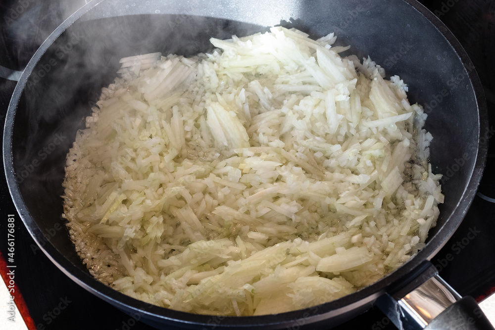 finely chopped onions sauteing in deep frying pan at home kitchen finely chopped onions sauteing in deep frying pan at home kitchen
