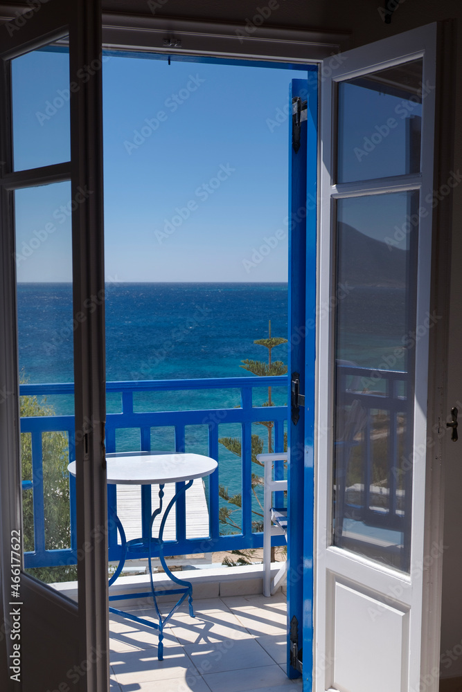 Greek balcony window open on the sea view. Typical small table white and blue. Photo taken in Koufonisia island. Greece
