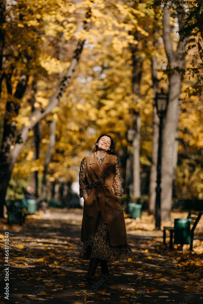 Happy young woman smiling, walking on an alley in a park on warm autumn day. Happy young woman smiling, walking on an alley in a park on warm autumn day.
