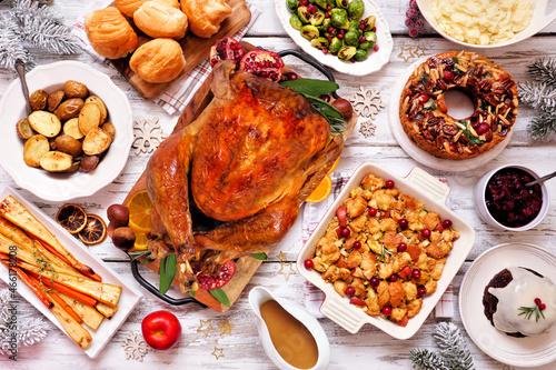 Classic Christmas turkey dinner. Top view table scene on a white wood background. Turkey  potatoes and sides  dressing  fruit cake and plum pudding.