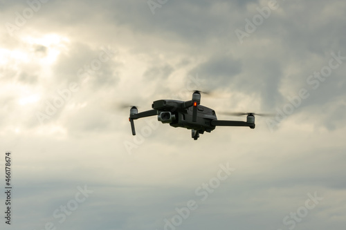 A drone hovering in the cloudy sky.