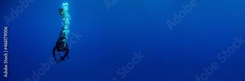 Tableau sur toile Blue background banner with a scuba diver entering water in a vertical position