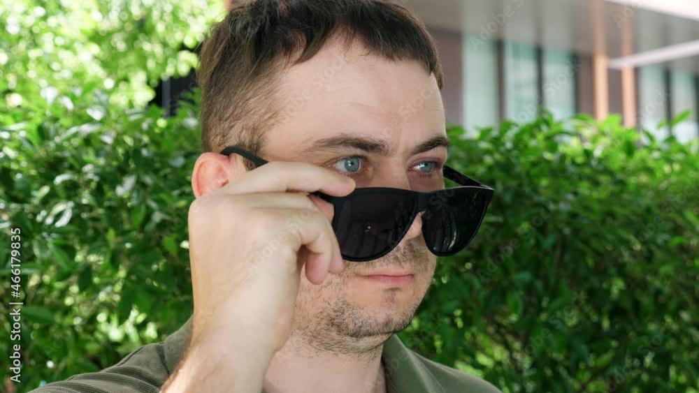 Portrait of Sad Man Pulls Down Black Sunglasses, Hiding Injured Red Eye after Insect Bite. Male with Inflamed and Affected Conjunctivitis Eye Looks Over Glasses. Man with Season Allergy on Bloom Portrait of Sad Man Pulls Down Black Sunglasses, Hiding Injured Red Eye after Insect Bite. Male with Inflamed and Affected Conjunctivitis Eye Looks Over Glasses. Man with Season Allergy on Bloom