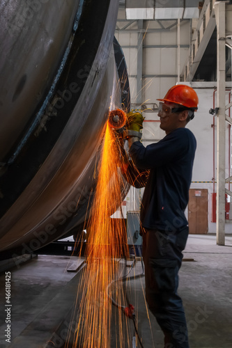 Manufacturing of steel pipes in one of the plant's workshops. Rotation of the angle grinder disc during operation. Bright sparks from metal cutting. Preparation of metal structures before welding.