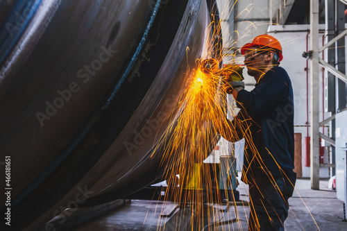 Manufacturing of steel pipes in one of the plant's workshops. Rotation of the angle grinder disc during operation. Bright sparks from metal cutting. Preparation of metal structures before welding.