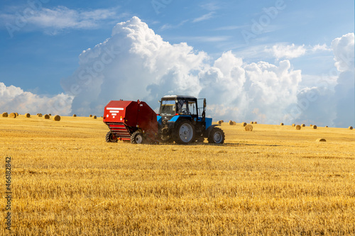 Bales of Hay in the Countryside and Tractor at Work in the background.