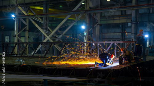 Assembly of metal structures in the production workshop. Working with an angle grinder. Night shift work.