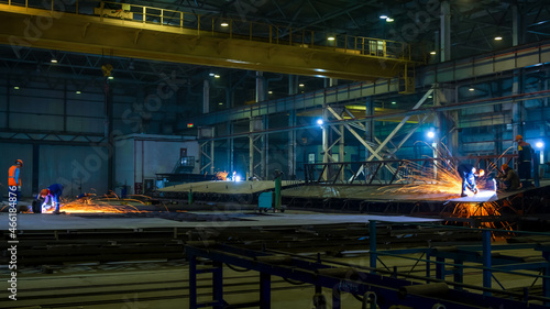 Assembly of metal structures in the production workshop. Working with an angle grinder. Night shift work.