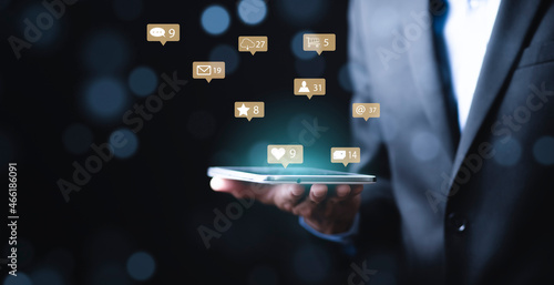 Businessman holding tablet with communication message icons of mail, Marketing business sending information to customers, Customer service call center contact us. Email marketing and newsletter. © Bussarin