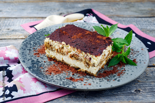 Modern style traditional Italian tiramisu served as close-up on a Nordic design gray plate on a wooden board with copy space