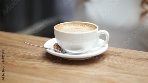 Side view of white cup of black coffe on light wooden table background. Media. Closeup shot of cup of coffee.