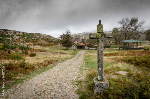 a Christian cross made of stone in front of the chapel of Nossa Senhora da Laje, Serra da Freita mountain, Municipality of Arouca, Aveiro District, Portugal