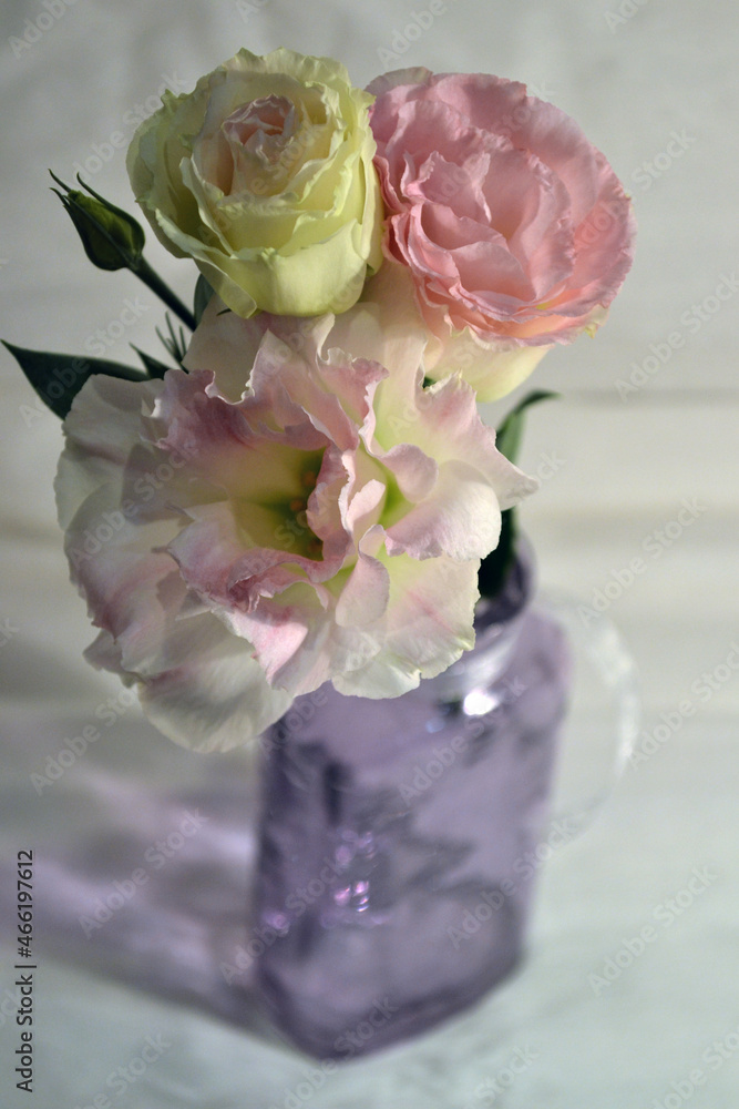 Obraz premium Bouquet of eustomas in a purple glass bottle