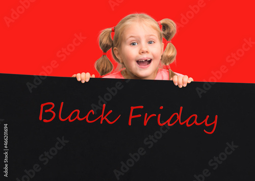 Funny little girl holding black board with Black Friday on red background. Sale discount concept.