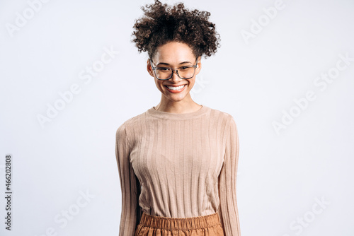 Successful handsome beautiful curly hair young stylish woman in casual closes standing and looking at camera with toothy smile. Studio shot isolated on white background