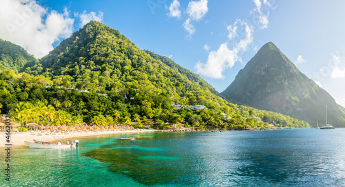 Caribbean beach with palms and straw umrellas on the shore with Gros Piton mountain in the background, Sugar beach, Saint  Lucia photo
