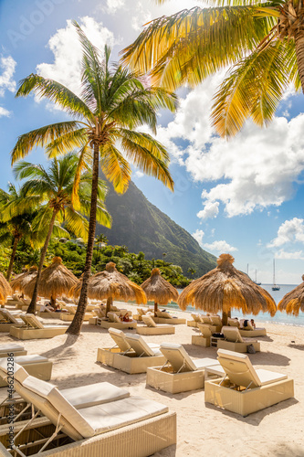 Caribbean beach with palms and straw umrellas on the shore with Gros Piton mountain in the background, Sugar beach, Saint Lucia