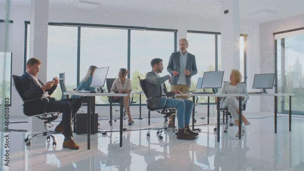 Informal discussion in work. People speaking and gesturing in room with large windows. Modern open space office interior. Informal discussion in work. People speaking and gesturing in room with large windows. Modern open space office interior.