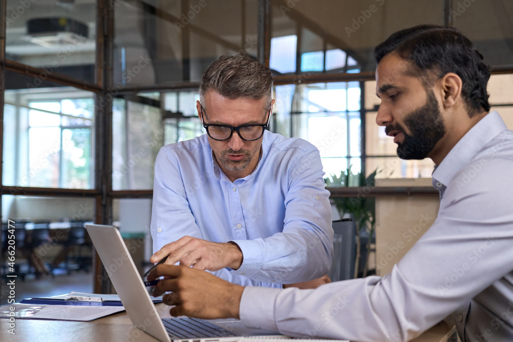Fototapeta premium Diverse business people businessmen negotiating at boardroom meeting using working on laptop pc computer. Multiethnic executive team discussing financial partnership sitting at table in office.