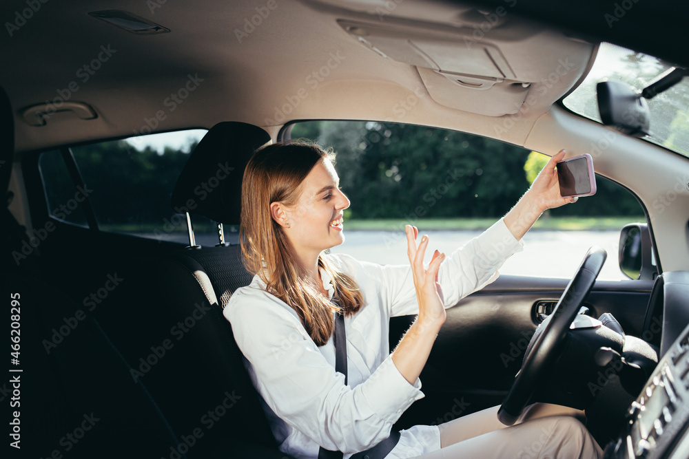 Woman driver in the car businesswoman well dressed talking on a video call of a mobile phone in the parking lot Woman driver in the car businesswoman well dressed talking on a video call of a mobile phone in the parking lot