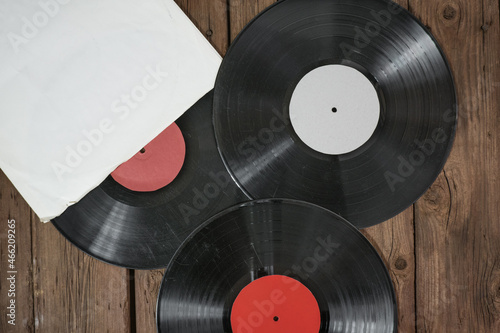 Three old vinyl records in paper case on wooden rustic background.