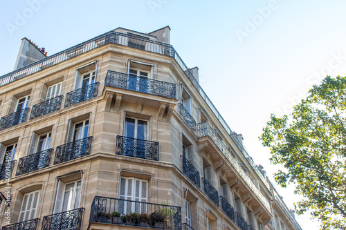Close, upward exterior view of traditional building architecture in France, with stone walls and beautiful ornate French balconettes © Cynthia