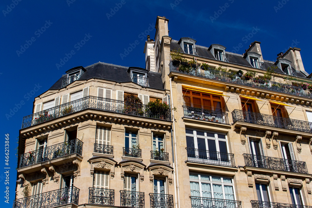 Close, upward exterior view of traditional building architecture in France, with stone walls and beautiful ornate French balconettes