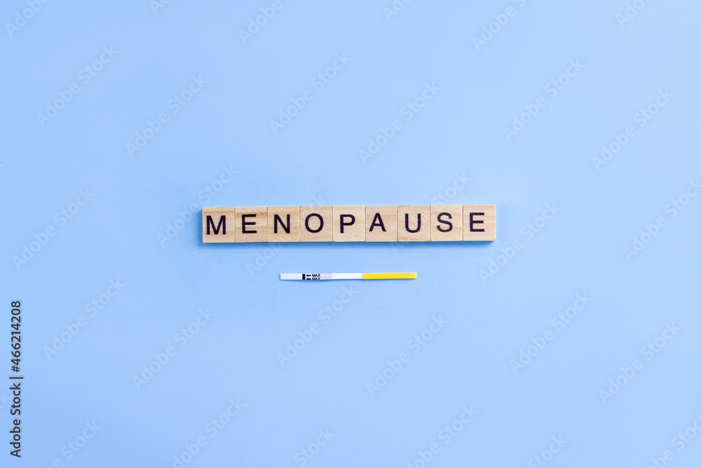 Obraz premium Word menopause on wooden blocks with letters and rapid FSH test. Minimal concept of female periods. Copy space
