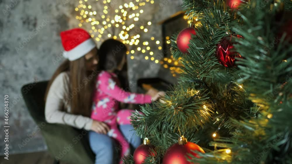 Mom teaching her daughter to play a new year song on the piano on christmas eve in a decorated room in santa hat, new year mood, tree in focus Mom teaching her daughter to play a new year song on the piano on christmas eve in a decorated room in santa hat, new year mood, tree in focus