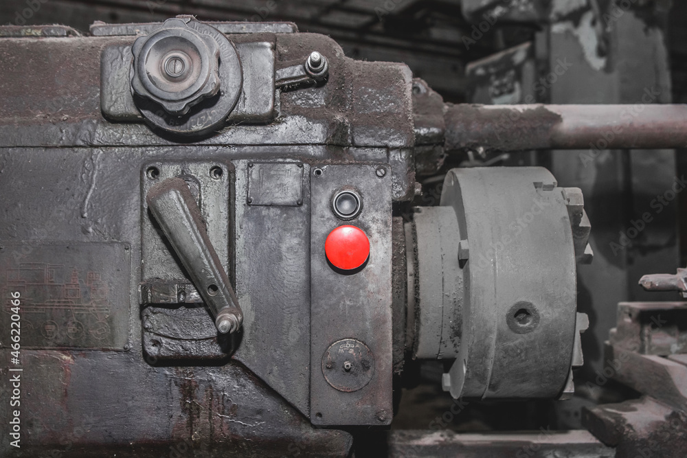 Red start button for controlling old milling machine equipment in the workshop at the industrial plant