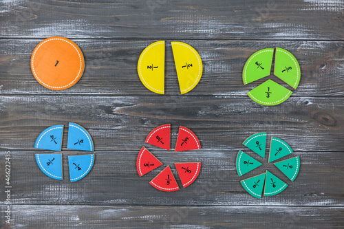 Multicolored fractions on gray wooden table. Back to school, fun math, games for kindergarten, preschool education.
