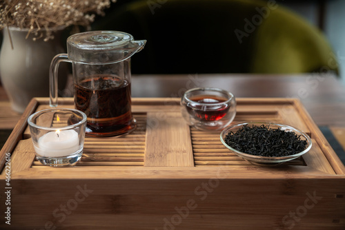 Beautiful indoor scene with Chinese tea items as tea pot, tea glass and black tea on traditional indoor environment