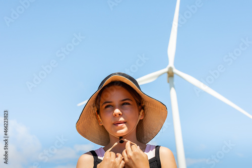 Criança num parque eólico gerando energia e protegendo o meio ambiente.