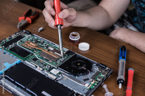 A man repairs a laptop and motherboard with a soldering iron. Laptop repair.