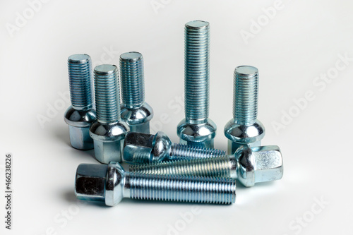 Large car wheel bolts made of silver metal. Isolated over white background. close-up